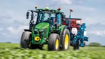 John Deere Traktor der Serie 6M auf dem grünen Feld