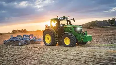 Trecker auf dem Acker bei Sonnenaufgang