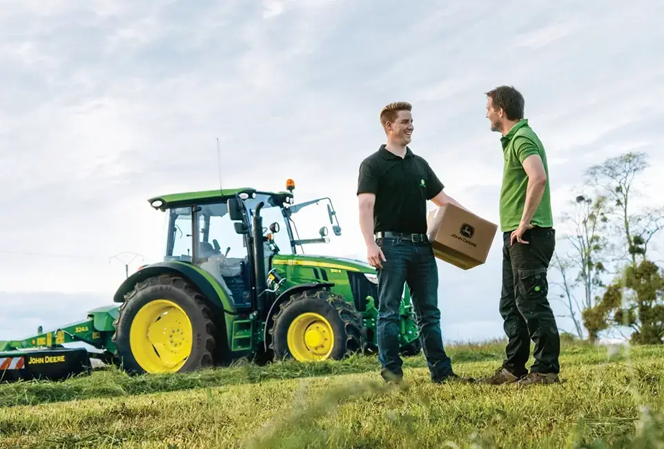 2 Männer auf dem Feld, John Deere Traktor im Hintergrund