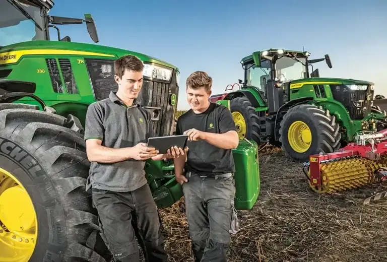 2 Männer auf dem Feld, John Deere Traktoren im Hintergrund