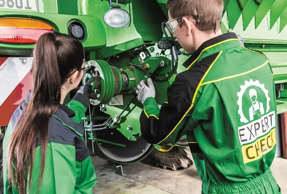 Junger Mann und junge Frau arbeiten an einer John Deere Maschine in der Werkstatt