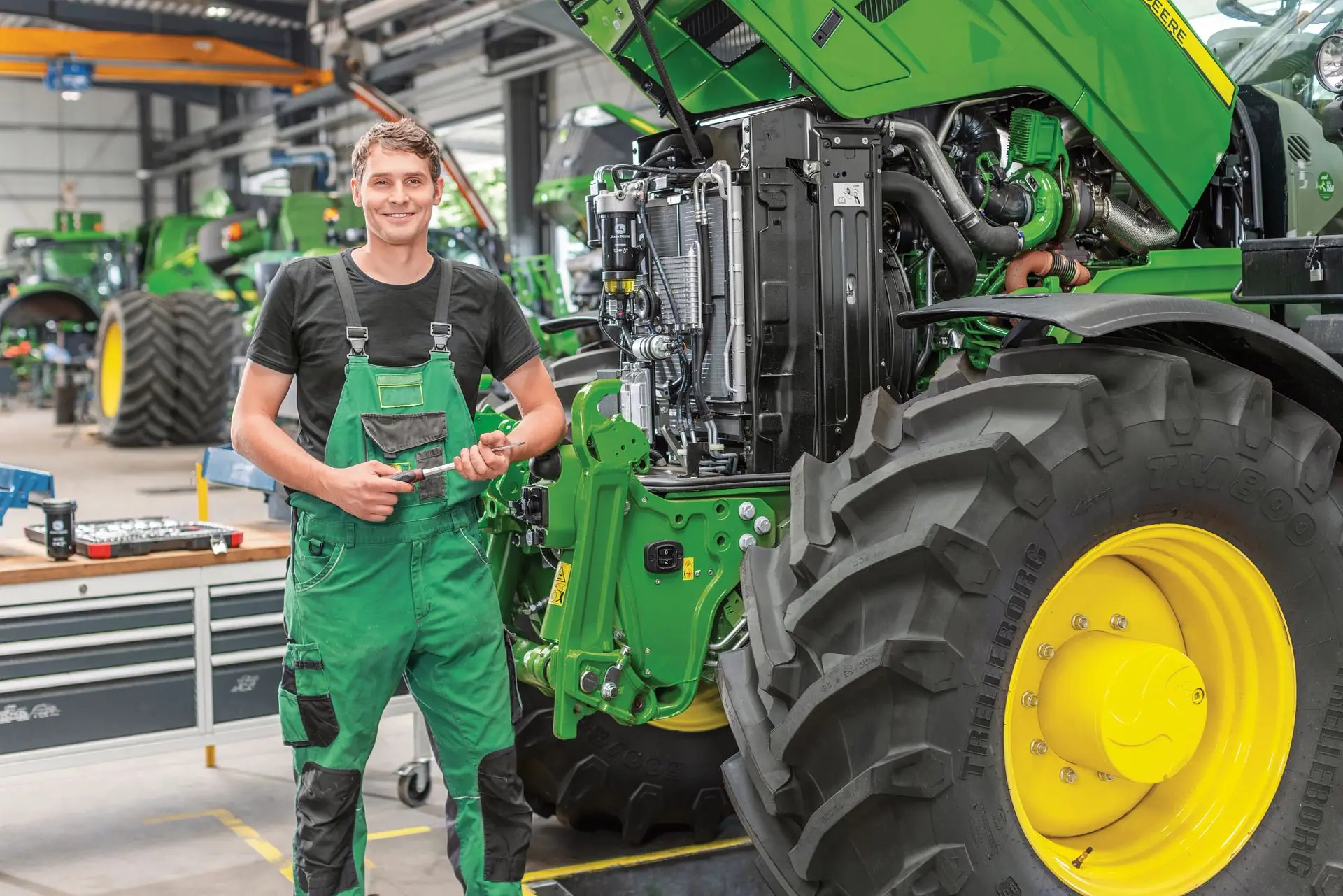 Mann mit Werkzeug in der Hand in Werkstatthalle