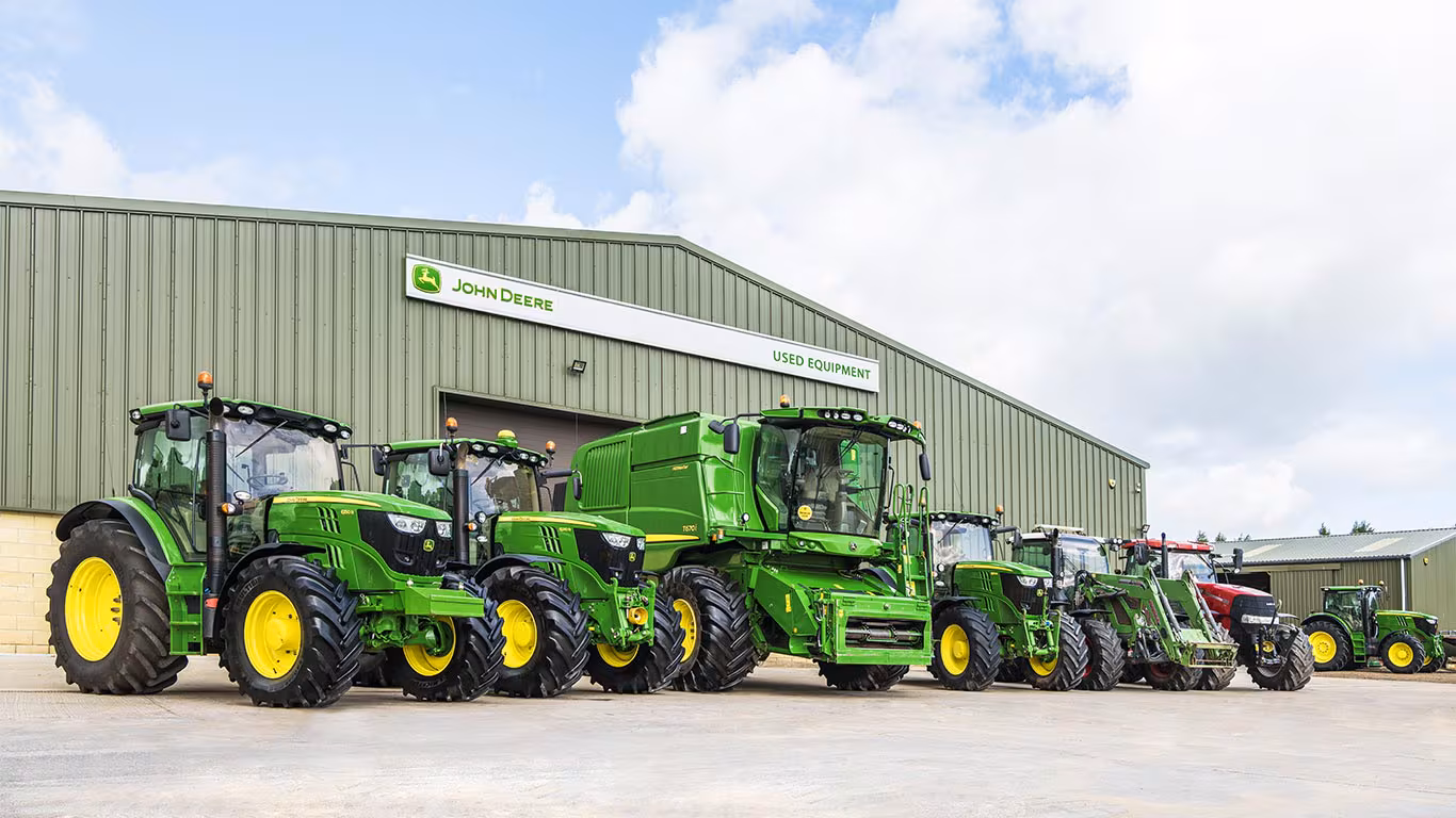 John Deere Maschinen auf einem Hof, im Hintergrund eine Halle